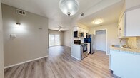 This well-appointed 3-bedroom, 2-bathroom single-story home in Dallas, Texas offers a functional and modern layout. An entry hallway with wall sconce lighting opens into a bright, open-concept living and kitchen area. The living room features vaulted ceilings, a ceiling fan, a marble-surround fireplace, and large sliding glass doors that invite natural light and provide access to a private patio with outdoor views. The kitchen is thoughtfully designed with white shaker cabinetry, granite-style countertops, a mosaic tile backsplash, a stainless steel sink, and a full suite of stainless steel appliances including a refrigerator, electric range, microwave, and dishwasher. Hardwood-style luxury vinyl flooring runs throughout the main living areas, while the bedrooms feature plush carpeting and ceiling fans. Each bedroom includes a dedicated closet, with the primary bedroom offering generous proportions. Both bathrooms are finished with large-format marble-style tile surrounding soaking tub and shower combinations, accented by decorative mosaic niches. Textured ceilings and neutral-toned walls provide a clean, cohesive aesthetic throughout this move-in-ready Dallas home.