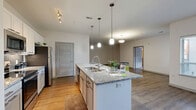 Located at 601 Avenida Cesar E Chavez in Kansas City, MO, this well-appointed 2-bedroom, 2-bathroom residence offers a thoughtfully designed single-level floor plan with generous living space. The open-concept kitchen, dining, and living area serves as the heart of the home, anchored by a large granite-topped kitchen island with a double sink and elegant pendant lighting. The kitchen is outfitted with white cabinetry, a subway tile backsplash, stainless steel appliances, and ample counter space, making it as functional as it is attractive. Wood-style plank flooring flows throughout the main living areas, adding warmth and continuity. The living room features multiple windows that invite natural light and provide views of the surrounding neighborhood. Both bedrooms are carpeted and offer a comfortable, quiet retreat, each with access to well-sized closets fitted with wire shelving systems. The primary bathroom includes a dual-sink granite vanity with gray cabinetry and a large mirror, reflecting a consistent design aesthetic. A private balcony, utility room, and four closets round out the practical features of this residence, delivering both comfort and functionality in a modern Kansas City setting.