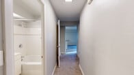Located at 1000 8th Ave in Seattle, WA, this one-bedroom, one-bathroom residence offers a practical and well-organized single-floor layout. The living room is a bright, open space featuring plush carpeting, two large windows that invite generous natural light, and wall-mounted heating units that ensure year-round comfort. Urban views of the surrounding Seattle cityscape are visible through the windows, adding to the city-connected ambiance.

The kitchen is efficiently designed with white cabinetry, laminate countertops, and wood-style flooring. It is fully equipped with a full-size refrigerator, electric range, dishwasher, and a stainless sink — providing all the essentials in a compact, functional arrangement.

The bedroom is a comfortably sized retreat with soft carpeting, natural light streaming through a window, and a built-in closet offering dedicated storage. A hallway connects the main living areas to the bedroom and bathroom, maintaining a logical and private flow throughout the unit.

The bathroom features tile flooring, a white vanity with under-sink storage, a mirrored medicine cabinet, glass shelving, and a shower-tub combination with tiled surround. Clean, neutral tones carry throughout the entire residence, creating a cohesive and understated aesthetic well-suited to urban living.