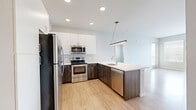 Located at 150 Main St in Longmont, Colorado, this thoughtfully designed residence offers 2 bedrooms, 3 bathrooms, and a well-utilized single-floor layout. The open-concept kitchen and living area serves as the heart of the home, anchored by light wood-style flooring that flows throughout the main spaces. The kitchen is outfitted with stainless steel appliances, including a refrigerator, range, and microwave, complemented by white upper cabinetry, wood-toned lower cabinets, a subway tile backsplash, and a peninsula with a sink — ideal for both cooking and casual dining. A pendant light fixture adds a modern touch overhead. The living area benefits from large windows and a sliding glass door that invite generous natural light and provide outdoor views. The primary bedroom is a comfortable retreat, featuring soft carpet, exposed ductwork that lends an industrial accent, and direct sightlines to the kitchen. The secondary bedroom also offers carpeted floors and multiple windows with exterior views. Both closets include wire shelving systems for organized storage. The three bathrooms are finished with clean, contemporary fixtures — including a soaking tub with large-format tile surround and a vanity with dark wood cabinetry and white countertops.