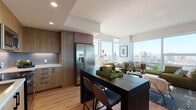 Located in the heart of downtown San Diego, this contemporary high-rise residence at 1150 E Street offers a thoughtfully designed open-concept floor plan bathed in abundant natural light. Expansive floor-to-ceiling windows frame sweeping panoramic views of the San Diego skyline and beyond, creating a striking backdrop throughout the living spaces.

The open kitchen is outfitted with warm wood cabinetry, a sleek tile backsplash, stainless steel appliances, and a dark-toned central island with bar seating — ideal for both cooking and casual dining. The kitchen flows seamlessly into the living area, where large-format windows and balcony access maximize the elevated city views.

The living room is bright and airy, anchored by a sectional sofa and generous windows overlooking the urban landscape. A separate den or flex space provides additional room for a home office or reading nook, also benefiting from natural light and city views.

The bedrooms are well-appointed with large windows, light hardwood flooring, and tranquil outlooks over the cityscape. The bathroom features marble-style tile throughout, a soaking tub, and a separate shower, lending a clean, spa-like aesthetic.

Light hardwood flooring runs throughout the residence, tying together the modern, cohesive design of this elevated downtown San Diego home.