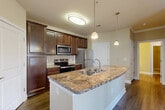Located at 1836 Roswell St SE in Smyrna, Georgia, this well-appointed one-bedroom, one-bathroom residence offers a thoughtfully designed single-floor layout that maximizes every square foot. The heart of the home is an open-concept kitchen, dining, and living area centered around a generous granite-topped kitchen island with a stainless steel sink and elegant pendant lighting overhead. Rich dark-wood cabinetry lines the kitchen walls, complemented by a tile backsplash and a full suite of stainless steel appliances, including a refrigerator, electric range, and built-in microwave. Hardwood-style flooring flows throughout the main living areas, adding warmth and continuity to the space. The bedroom is a comfortable retreat featuring plush carpet, a ceiling fan with light fixture, and a window that invites natural light. Two closets, including a spacious walk-in with wire shelving, provide ample storage. The bathroom features a dark-wood vanity with light countertop, a well-lit mirror, and wood-look tile flooring. A dedicated utility room and pantry add practical functionality. Crown molding accents select areas, contributing to a clean, polished finish throughout this move-in-ready Smyrna residence.