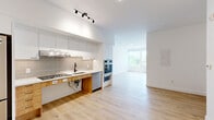 Located at 1600 James Naismith Dr in Ottawa, this thoughtfully designed 2-bedroom, 2-bathroom unit offers a clean, modern aesthetic across a well-proportioned single-floor layout. Light oak hardwood flooring flows consistently throughout, complementing the crisp white walls and creating a bright, cohesive feel.

The kitchen is a standout feature, equipped with sleek white upper cabinetry, warm wood lower drawers, a neutral subway tile backsplash, and a full suite of stainless steel appliances including a gas cooktop, double wall oven, dishwasher, and refrigerator. Track lighting overhead adds a contemporary touch, and the kitchen opens directly to the living area, which benefits from large floor-to-ceiling windows framing views of the surrounding greenery.

The primary bedroom is a well-sized retreat with sliding panel doors, while the second bedroom features expansive corner windows that flood the room with natural light. Both rooms include smooth white sliding closet doors with matte black hardware.

The two bathrooms are finished with vertically stacked white subway tile and hexagonal floor tile, with matte black fixtures lending a modern contrast. One bathroom features a soaking tub with overhead shower, while the other offers a walk-in shower. A stacked in-unit washer and dryer adds everyday convenience.
