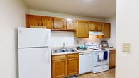 Located at 2494 Arrowhead Circle in South Bend, Indiana, this single-story unit offers a straightforward, functional layout designed for comfortable everyday living. The kitchen serves as a practical hub of the space, outfitted with warm honey-oak upper and lower cabinetry providing generous storage throughout. White appliances, including a refrigerator, electric range, dishwasher, and an under-cabinet range hood, line the walls alongside a double-basin sink with a single-handle faucet. Light tile flooring completes the kitchen's clean, utilitarian look.

The living and bedroom areas feature wall-to-wall carpeting in a neutral beige tone, contributing to a soft, quiet atmosphere. White walls and standard ceilings keep the interiors bright and neutral, while multiple windows allow natural light to filter in and offer views of surrounding greenery. The 3D floorplan reveals a compact but efficient arrangement that includes a dedicated laundry area with side-by-side washer and dryer connections.

The bathroom is appointed with a wood-toned vanity cabinet, a white countertop with sink, a large wall mirror with overhead lighting, tile flooring, and a tub-shower combination. Overall, the space presents a clean, move-in-ready environment with a practical design suited to everyday use.