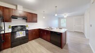 Located at 127 Madison St in Elyria, Ohio, this single-floor, one-bedroom, one-bathroom unit offers a well-designed layout that maximizes functionality within a compact footprint. The open-concept living and kitchen area serves as the heart of the home, featuring rich dark cherry cabinetry, light-toned countertops, and a peninsula with bar seating illuminated by stylish pendant lighting. Black appliances — including a refrigerator, range, and dishwasher — complete the kitchen, which flows seamlessly into the living area finished with light hardwood-style flooring. A ceiling fan in the living space and a window overlooking the outdoors add comfort and natural light to the area. The bedroom is a calm, carpeted retreat with a natural light source provided by a window with blinds. It connects directly to a walk-in closet outfitted with wire shelving for organized storage. The bathroom is thoughtfully designed with accessibility in mind, featuring grab bars near the toilet and shower area, a wood-vanity with a white countertop, and easy-maintenance hard flooring. Neutral tones and clean finishes throughout the unit create a cohesive, move-in ready atmosphere suited for a range of lifestyles.
