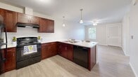 Located at 127 Madison St in Elyria, Ohio, this single-floor, one-bedroom, one-bathroom unit offers a well-designed layout that maximizes functionality within a compact footprint. The open-concept living and kitchen area serves as the heart of the home, featuring rich dark cherry cabinetry, light-toned countertops, and a peninsula with bar seating illuminated by stylish pendant lighting. Black appliances — including a refrigerator, range, and dishwasher — complete the kitchen, which flows seamlessly into the living area finished with light hardwood-style flooring. A ceiling fan in the living space and a window overlooking the outdoors add comfort and natural light to the area. The bedroom is a calm, carpeted retreat with a natural light source provided by a window with blinds. It connects directly to a walk-in closet outfitted with wire shelving for organized storage. The bathroom is thoughtfully designed with accessibility in mind, featuring grab bars near the toilet and shower area, a wood-vanity with a white countertop, and easy-maintenance hard flooring. Neutral tones and clean finishes throughout the unit create a cohesive, move-in ready atmosphere suited for a range of lifestyles.