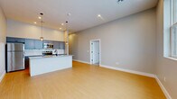 Located on State Street in Schenectady, NY, this thoughtfully designed 2-bedroom, 1-bathroom unit offers a clean, contemporary aesthetic across a well-utilized single floor. The open-concept living and kitchen area serves as the heart of the home, anchored by a striking island with granite countertops and a matte black sink faucet. The kitchen is outfitted with gray shaker-style cabinetry, a white subway tile backsplash, stainless steel appliances, and stylish industrial pendant lighting — creating a functional yet visually appealing space. Light bamboo hardwood flooring flows throughout the main living areas, complementing the neutral gray walls and crisp white trim. A bright, windowed living area opens seamlessly from the kitchen, offering a spacious and airy feel. Both bedrooms are carpeted for comfort and feature natural light from individual windows with clean-lined white frames. The primary bedroom provides a comfortable footprint and includes a closet with paneled white doors and matte black hardware. The full bathroom is finished with tile flooring, matte black accessories, and a tub-shower combination. A hallway with recessed lighting and built-in HVAC vents connects the rooms efficiently, completing this clean, move-in-ready residence.