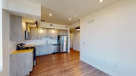 This contemporary single-floor residence offers a thoughtfully designed layout with a clean, modern aesthetic throughout. The open-concept kitchen seamlessly connects to the living area, creating an inviting and functional space. The kitchen is outfitted with light wood cabinetry, bold yellow countertops, a white subway tile backsplash, and a full suite of stainless steel appliances including a refrigerator, electric range, built-in microwave, and dishwasher. Track lighting and recessed ceiling lights illuminate the space effectively, while large windows allow natural light to pour in.

Warm wood-look flooring extends consistently throughout the entire residence, lending a cohesive and contemporary feel. The bedrooms are generously proportioned, each featuring ceiling fans, ample natural light from large windows with vertical blinds, and access to closets — including at least one walk-in closet with built-in shelving and hanging rods.

The two bathrooms are finished with light wood vanities, stone-toned countertops, large framed mirrors, and wood-look flooring. One bathroom includes a full shower-tub combination, while the other features a more compact layout. The overall ambiance is bright, clean, and move-in ready, with neutral walls and modern fixtures throughout.