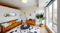Located on S Fifth Ave in the heart of Minneapolis, this single-floor unit offers a thoughtfully designed layout with modern finishes and a cohesive aesthetic throughout. The living area serves as the centerpiece of the space, featuring light hardwood-style flooring, neutral walls, and a large window that frames views of the surrounding urban skyline, filling the room with natural light. The mid-century modern furnishings complement the clean architectural lines, creating a warm and inviting atmosphere.

The kitchen is well-equipped with slate-gray cabinetry, stainless steel appliances including a range, microwave, dishwasher, and refrigerator, all set against crisp white countertops and a subway tile backsplash. Open shelving adds a stylish, functional touch, while a central island with matching cabinetry provides additional prep and dining space. Light hardwood-style flooring flows seamlessly from the kitchen into the surrounding areas.

The bedroom is a calm retreat with neutral walls, soft carpet underfoot, and tasteful framed artwork. A bedside lamp and dark-framed bed add contrast to the light color palette. The full bathroom features hardwood-style flooring, a tub-shower combination with a striped curtain, and a clean, minimal design with white fixtures throughout.