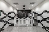 Located at 401 N Main St in Santa Ana, California, this purpose-built pet grooming space is thoughtfully designed with both functionality and visual flair in mind. The single-floor layout is anchored by a dramatic floor-to-ceiling photographic mural of a dog's face, serving as an eye-catching focal point at the far end of the room.

The interior is defined by bold black-and-white subway tile work arranged in geometric, diamond-patterned designs that line the walls throughout. The tiling not only adds a striking aesthetic but also ensures surfaces are durable and easy to maintain — ideal for a grooming environment. Polished concrete floors complement the monochromatic palette while providing practicality underfoot.

The grooming area features dedicated stations equipped with adjustable grooming tables and mounted hose attachments, as well as a stainless steel wash station for bathing pets. White picket-style dividers separate the individual grooming bays, adding a charming detail to the otherwise modern design.

Recessed ceiling lighting and flush-mounted HVAC units ensure the space is well-lit and climate-controlled. Near the entrance, a welcoming waiting area features lush potted plants, a simple bench, and decorative accents, creating a calm and inviting atmosphere for both pets and their owners. The overall design balances professional utility with a polished, distinctive aesthetic.