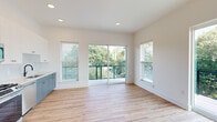 Located at 1015 Boulevard SE in Atlanta's Grant Park neighborhood, this single-floor unit showcases a clean, modern design characterized by light hardwood flooring, crisp white walls, and matte black hardware accents carried consistently throughout the space.

The open kitchen is a standout feature, pairing tall white upper cabinetry with slate-blue lower cabinets and a white subway tile backsplash. Stainless steel appliances, including a French door refrigerator, gas range, built-in microwave, and dishwasher, complete the setup. Recessed lighting and an adjacent window ensure the kitchen remains bright and functional.

The main living area is generously proportioned, flooded with natural light through multiple large windows and sliding glass doors that open directly onto a private balcony. The balcony, framed by modern cable-and-grid metal railings, offers expansive views of Atlanta's lush tree canopy — a notably serene outlook for an urban setting. A second balcony provides additional outdoor access with equally scenic greenery views.

Bedrooms feature large windows, light-filled interiors, and access to a spacious walk-in closet equipped with wire shelving systems. The bathroom is well-appointed with a slate-blue vanity, matte black fixtures, gold accent lighting, a framed mirror, and a glass-enclosed tiled shower. A hallway with a louvered closet door adds practical storage to the layout.