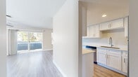 Located at 1525 E Baseline Rd in Tempe, Arizona, this single-story 2-bedroom, 2-bathroom residence offers a clean, modern aesthetic with a thoughtfully designed layout. Light wood-style flooring runs throughout the home, complementing the neutral warm-beige tones on every wall and creating a cohesive, airy feel.

The living room is a standout space, bathed in natural light streaming through large sliding glass doors that open to an outdoor balcony area with views of surrounding greenery. A ceiling fan adds comfort and character to the room. The adjacent kitchen is well-equipped with white shaker-style cabinetry, light countertops, stainless steel appliances including a refrigerator, range, microwave, and dishwasher, and a galley-style layout that maximizes functionality.

The primary bedroom offers a comfortable footprint with a ceiling fan, a window with natural light, and access to hallway areas. The second bedroom is equally bright, also featuring a ceiling fan and window. Both bathrooms are finished with white vanity cabinetry, light countertops, wood-style flooring, and tub-shower combinations. A dedicated closet provides additional storage. Two hallways connect the rooms efficiently, rounding out this well-organized and move-in-ready home.
