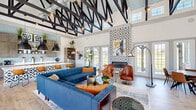 Located in Tyler, TX, this single-floor community space delivers a compelling blend of architectural drama and contemporary design. The centerpiece of the interior is the soaring ceiling fitted with bold, exposed black steel trusses set against a pale blue-painted deck, creating a visually dynamic overhead canopy that draws the eye upward and reinforces the sense of expansive vertical scale throughout the main hall.

The open-concept layout seamlessly connects the living area and kitchen, with light wood-look flooring running throughout and an abundance of natural light streaming in through multiple sets of French doors and tall transom windows. A grand double-door entry welcomes visitors into a bright foyer with high ceilings, flanked by large windows and accented by decorative wall-mounted planters with trailing greenery.

The living area features a dramatic floor-to-ceiling geometric patterned fireplace surround that serves as a striking focal point, complemented by comfortable modern seating arrangements. The kitchen is well-appointed with gray shaker cabinetry, a light blue glass tile backsplash, an expansive quartz-topped island with bar seating, open display shelving, and three oversized matte black pendant lights. The overall ambiance is modern, vibrant, and welcoming.