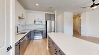 Located at 2020 Winters Eve Dr in Charlotte, NC, this well-designed two-bedroom, two-bathroom single-floor residence offers a comfortable and functional layout. The open-concept living area seamlessly connects the living room, dining area, and kitchen, creating an inviting communal space. A ceiling fan with a sleek matte black finish anchors the living room, which features light hardwood-style flooring throughout.

The kitchen is outfitted with two-tone cabinetry — white upper cabinets paired with gray lower cabinets — complemented by a white tile backsplash, quartz countertops, a kitchen island with bar seating, and stainless steel appliances including a refrigerator, range, and microwave. The dining area benefits from large windows that bring in abundant natural light and neighborhood views.

Both bedrooms are carpeted and include ceiling fans, with the primary bedroom offering access to a walk-in closet featuring wire shelving. The bathrooms are finished with gray vanity cabinetry, framed mirrors, matte black hardware, and wood-look tile flooring. A dedicated laundry room houses a full-size washer and dryer with overhead wire shelving for additional storage.