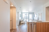 This contemporary single-floor residence is designed with a clean, modern aesthetic and thoughtful layout throughout. The open-concept kitchen flows seamlessly into the living area, creating a connected and functional space. The kitchen is well-equipped with stainless steel appliances, including a gas range, microwave, and refrigerator, complemented by warm wood cabinetry, white upper cabinets, light quartz countertops, and a grey subway tile backsplash. A kitchen island with a built-in sink adds both workspace and casual dining convenience.

The living area features light hardwood-style flooring that runs throughout, recessed lighting, and large windows that invite generous natural light and urban views. The space offers a relaxed yet stylish ambiance.

Both bedrooms are bright and comfortable, each benefiting from large windows with city views. The primary bedroom includes a distinctive textured accent wall and connects to an ensuite bathroom featuring a dual-sink vanity with warm wood cabinetry, a walk-in shower with tile surround, and an adjacent walk-in closet. A second full bathroom with a soaking tub and single vanity serves the additional bedroom. A dedicated in-unit stacked washer and dryer adds everyday convenience, completing this well-appointed modern residence.