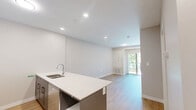 Located at 1100 Afton Dr in Windsor, Ontario, this one-bedroom, one-bathroom unit offers a thoughtfully designed layout with modern finishes throughout. The open-concept kitchen and living area forms the heart of the space, anchored by a striking blue kitchen island with a crisp white countertop and integrated sink. White upper cabinetry, stainless steel appliances — including a refrigerator and electric range — and recessed pot lighting complete the kitchen's clean, contemporary aesthetic. Light oak-toned hardwood flooring flows seamlessly throughout the entire unit, lending warmth and visual continuity.

The bedroom is a comfortable, well-proportioned room featuring a large window that invites natural light and provides views of the surrounding greenery. A set of sleek, floor-to-ceiling sliding closet doors with matte black hardware adds a modern touch while maximizing storage efficiency. Neutral warm-grey walls throughout the unit create a calm and cohesive atmosphere.

The bathroom is finished in a clean, minimalist style with a white vanity, white countertop, and light hardwood-style flooring consistent with the rest of the unit. A sliding door with matte black hardware provides a stylish and space-conscious entry. Overall, the unit presents a modern, move-in-ready living space with consistent design details and quality finishes.