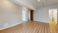 Located at 888 Delaware Ave in Buffalo, NY, this thoughtfully designed 2-bedroom, 2-bathroom residence offers a seamless blend of modern finishes and functional layout across a single floor. Light-toned luxury vinyl plank flooring flows consistently throughout the space, creating a bright, cohesive aesthetic.

The open-concept kitchen and living area serves as the heart of the home. The kitchen is equipped with stainless steel appliances, crisp white cabinetry, a quartz-topped island with pendant lighting, and a deep sink beneath a window that brings in natural light. Exposed ductwork adds an industrial character to the otherwise clean, contemporary design.

A long hallway with exposed overhead ducting connects the main living area to the private bedrooms and bathrooms. The generously sized primary bedroom features built-in shelving and a closet, while the second bedroom includes a closet and additional wall shelving, offering versatile storage. One bedroom also showcases an original painted concrete block wall, lending an urban loft character.

Both bathrooms are finished with white cabinetry, dark-topped vanities, and walk-in glass-door showers. One bathroom features an oversized sliding glass shower enclosure, while the other offers a sleek frameless-style design. The overall ambiance is clean, modern, and move-in ready.