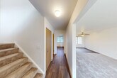 Located at 1300 Hillside Rd in Albion, Michigan, this three-bedroom, two-bathroom home spans three floors, offering a well-organized and functional layout. The main level features a welcoming hallway with hardwood-style flooring that flows toward the living room, which is finished with plush carpeting, a ceiling fan, and a large window fitted with vertical blinds that allow ample natural light. The kitchen is equipped with warm oak cabinetry, a double sink, white appliances including a range and refrigerator, and a window overlooking the outdoors. An adjacent dining area completes the main living space. The bedrooms are carpeted and each include ceiling fans and generous closet space, with several rooms featuring sliding or hinged wood-panel closet doors. The two bathrooms are finished with wood-tone vanities, countertop sinks, and hardwood-style flooring; the full bathroom includes a tub-shower combination. A utility basement provides additional functional space, housing the water heater, a utility sink, and exposed overhead systems, with a painted concrete floor and windows for ventilation. With six closets distributed throughout, storage is plentiful across all levels of this practical Albion home.