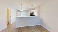Located at 305 Hummingbird Ln in Oxford, NC, this two-story home offers a thoughtfully designed layout spread across two floors. The main level features an open-concept living area with warm light wood-style flooring, recessed lighting, and a ceiling fan that enhances airflow and comfort. The kitchen is a standout, outfitted with crisp white shaker cabinetry, stainless steel appliances including a French door refrigerator, electric range, and microwave, all complemented by light countertops and a peninsula with pendant lighting and bar seating — ideal for casual dining or entertaining. A convenient half bath is also located on the main floor. Upstairs, both bedrooms are carpeted and include ceiling fans, closets, and windows that allow natural light to filter in. The spacious primary bedroom offers a comfortable retreat with its own bathroom access. A full bathroom with a tub-shower combination and quartz-style vanity serves the upper level as well. A dedicated laundry room with washer hookups and overhead shelving adds everyday practicality. The staircase connects both floors seamlessly, completing this clean, move-in-ready home with a neutral, modern aesthetic throughout.