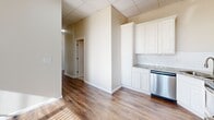 Located at 1912 11th St in Wichita Falls, TX, this one-bedroom, one-bathroom unit offers a well-designed single-floor layout that maximizes every square foot of its compact footprint. Warm hardwood-style flooring flows throughout the space, complemented by neutral wall tones and drop-panel ceilings fitted with ceiling fans, creating a bright and comfortable atmosphere.

The kitchen is a standout feature, outfitted with crisp white cabinetry, granite-style countertops, a subway tile backsplash, and a full suite of stainless steel appliances including a refrigerator, range, microwave, and dishwasher. The open sight lines from the kitchen into the hallway lend a connected, efficient feel to the layout.

The bedroom is generously proportioned, bathed in natural light through a large bank of windows dressed with vertical blinds, and fitted with a ceiling fan for year-round comfort. A dedicated closet with built-in shelving provides practical storage. The hallway leads seamlessly between rooms, maintaining a logical and comfortable flow.

The bathroom features floor-to-ceiling neutral tile surrounding a full soaking tub and shower combination, accented with brushed nickel fixtures and built-in shelving niches, delivering a clean, polished finish. Overall, this unit presents a thoughtfully updated interior with functional design and modern finishes throughout.