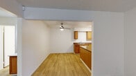 This single-story residence features a well-organized layout encompassing two bedrooms, two bathrooms, a kitchen, living room, and entrance. Light-toned wood-style flooring runs throughout the main living areas, while the bedrooms are finished with plush wall-to-wall carpeting, adding warmth and comfort. The living room is outfitted with a ceiling fan and opens directly to the kitchen, creating a connected and practical common area. The kitchen is well-appointed with warm wood-toned cabinetry, ample upper and lower storage, a double-basin sink, a peninsula counter for additional workspace, and white appliances including a range and refrigerator. Track lighting illuminates the kitchen workspace effectively. The bedrooms feature vertical blinds that allow for natural light control, with the primary bedroom offering a wall-mounted air conditioning unit for independent climate control. The bathrooms are clean and functional, featuring light wood-style flooring, a tub-shower combination, and vanity with mirror. Textured ceilings are consistent throughout the unit, contributing to its classic residential character. The entrance provides a defined transition into the home, completing this efficiently designed and move-in ready space.