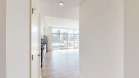 Located at 1810 State Street in San Diego's vibrant urban core, this thoughtfully designed residence offers a seamless open-concept layout connecting the kitchen and living areas. Light hardwood flooring runs throughout the space, complementing the bright, white interior walls and recessed lighting overhead.

The kitchen is a standout feature, outfitted with crisp white shaker cabinetry, dark countertops, a classic subway tile backsplash, and a full suite of stainless steel appliances including a gas range, microwave, dishwasher, and refrigerator. The space flows naturally into the living area, which is bathed in natural light from dramatic floor-to-ceiling windows and sliding glass doors that frame sweeping views of the downtown San Diego skyline.

Two bathrooms serve the residence; one features a subway-tiled tub and shower combination, while the other offers a stylish pedestal sink with an open metal frame, warm wood-tone flooring, and industrial-style vanity lighting. A dedicated walk-in closet provides generous storage with built-in shelving and hanging rods on multiple walls.

The overall ambiance is clean, modern, and light-filled, with the expansive city views serving as a defining backdrop throughout the living spaces.
