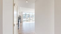 Located at 1810 State Street in San Diego's vibrant urban core, this thoughtfully designed residence offers a seamless open-concept layout connecting the kitchen and living areas. Light hardwood flooring runs throughout the space, complementing the bright, white interior walls and recessed lighting overhead.

The kitchen is a standout feature, outfitted with crisp white shaker cabinetry, dark countertops, a classic subway tile backsplash, and a full suite of stainless steel appliances including a gas range, microwave, dishwasher, and refrigerator. The space flows naturally into the living area, which is bathed in natural light from dramatic floor-to-ceiling windows and sliding glass doors that frame sweeping views of the downtown San Diego skyline.

Two bathrooms serve the residence; one features a subway-tiled tub and shower combination, while the other offers a stylish pedestal sink with an open metal frame, warm wood-tone flooring, and industrial-style vanity lighting. A dedicated walk-in closet provides generous storage with built-in shelving and hanging rods on multiple walls.

The overall ambiance is clean, modern, and light-filled, with the expansive city views serving as a defining backdrop throughout the living spaces.