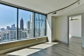 Located in the vibrant Midtown neighborhood of Atlanta, this single-floor residence at 882 Juniper St NE offers a contemporary urban living experience with refined finishes throughout. The open living area is anchored by expansive floor-to-ceiling windows that flood the space with natural light and frame breathtaking panoramic views of the Atlanta skyline and surrounding treetops. Light wood-tone flooring flows consistently throughout, complementing the neutral warm palette of the walls. A gracefully curved ceiling detail in the living area adds an architectural flourish, lending the space a sense of elegance and dimension. The kitchen is appointed with rich dark espresso cabinetry, light granite countertops, a classic subway-tile mosaic backsplash, and stainless steel appliances including a sleek range and over-the-range microwave. A deep double stainless steel sink with a brushed nickel faucet completes the polished culinary space. The bathroom continues the upscale aesthetic with large-format marble-look tile on both the floors and tub surround, a soaking tub with shower combination, and coordinating dark cabinetry with granite countertops. Brushed nickel fixtures and recessed lighting add a refined, cohesive finish throughout. This residence offers a sophisticated blend of modern design and practical comfort in one of Atlanta's most desirable neighborhoods.