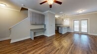 Located at 526 College Park Rd in Goose Creek, South Carolina, this two-story home offers a well-designed layout with modern finishes throughout. The main living area features rich hardwood-style flooring, crown molding, and a ceiling fan, creating an open and welcoming atmosphere. A built-in desk area with granite countertop and gray cabinetry adds a functional workspace adjacent to the living space.

The kitchen is a standout feature, equipped with gray shaker-style cabinetry, granite countertops, a peninsula with an undermount sink, and a full suite of stainless steel appliances including a refrigerator with ice maker, electric range, microwave, and dishwasher. Pendant lighting and a window provide ample illumination.

Multiple bathrooms are present, including one with a tub-shower combination and another with a glass-enclosed walk-in shower, both featuring granite vanity tops, gray cabinetry, and hardwood-style flooring. A dedicated laundry area houses a full-size washer and dryer with overhead wire shelving. Upstairs bedrooms are carpeted, fitted with ceiling fans, and benefit from natural light through multiple windows.