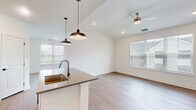 Located at Harbor Pointe Circle in Fruitland Park, FL, this well-designed single-story home offers a thoughtful layout with two bedrooms, two bathrooms, and a generous assortment of storage options including five closets and a pantry. The open-concept living, dining, and kitchen area serves as the heart of the home, featuring vaulted ceilings, recessed lighting, and a ceiling fan. Large windows invite ample natural light and outdoor views, enhancing the bright, airy atmosphere. The kitchen is a standout, showcasing white shaker cabinetry, a subway tile backsplash, granite countertops, stainless steel appliances, and a kitchen island with a matte black faucet and pendant lighting overhead. Light wood-look flooring flows throughout the main living areas and hallway. The spacious primary bedroom is carpeted and includes a ceiling fan and an en-suite bathroom with a soaking tub, dual-sink vanity with granite counters, and matte black fixtures. The second bedroom also features carpet, a ceiling fan, and a window with outdoor views. Additional highlights include a walk-in closet with wire shelving, a dedicated laundry room, a utility room, and a balcony, rounding out this clean, modern home.