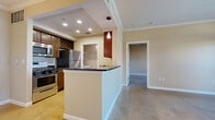 Located at 1951 Hunter Rd in San Marcos, TX, this well-appointed one-bedroom, one-bathroom residence offers a thoughtfully designed layout across a single floor. Polished concrete floors flow throughout the main living areas, lending a sleek, contemporary aesthetic complemented by crown molding and neutral warm-toned walls.

The open-concept kitchen is outfitted with rich dark wood cabinetry, dark granite countertops, stainless steel appliances including a gas range and refrigerator, and a built-in wine rack. A peninsula with pendant lighting connects the kitchen seamlessly to the combined dining and living area, which features a sliding glass door that fills the space with natural light and provides direct access to the private balcony. The covered balcony, framed by wood beams and iron railings, offers a tranquil view of a pond and surrounding greenery.

The spacious bedroom includes polished concrete floors, a ceiling fan, a window with outdoor views, and access to two closets. The full bathroom features a tiled tub-shower combination with a decorative mosaic accent border, dark wood vanity cabinetry, and a white countertop. A dedicated in-unit laundry room with shelving adds everyday convenience, completing this well-equipped residence.