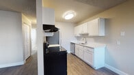 Located at 176 N Redwood Rd in Salt Lake City, Utah, this single-floor unit offers a practical and well-appointed layout across its living spaces. The open living area features durable hardwood-style flooring, a ceiling fan, and a wall-mounted PTAC heating and cooling unit, with natural light filtering in through a slatted window blind. The space flows seamlessly into the galley-style kitchen, which is outfitted with crisp white cabinetry, light quartz countertops, a stainless steel sink, and a full suite of appliances including an electric range with a ventilation hood, a stainless steel refrigerator, and a dishwasher. The bedrooms are finished with plush carpeting, neutral-toned walls, textured ceilings, and baseboard heating units. Each bedroom benefits from natural light through blinded windows, and at least one features a sliding closet door with built-in shelving and a hanging rod. The bathroom is cleanly finished with wood-style flooring, a white vanity with quartz countertop, a full tub-shower combination, and brushed nickel fixtures and hardware throughout. The overall aesthetic is clean, modern, and move-in ready.