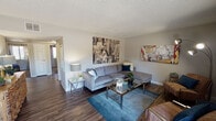 This single-floor residence offers a thoughtfully designed layout that balances comfort and functionality across its key living spaces. The living room serves as the heart of the home, featuring rich wood-look flooring, a textured ceiling, and generous wall space adorned with bold artwork. The open arrangement accommodates both a large sectional sofa and additional seating, creating a versatile space for relaxing and entertaining. A dedicated dining area sits adjacent to the living room, bathed in natural light from a window with white curtains, and comfortably fits a full dining table. The galley-style kitchen is well-equipped with white upper cabinetry, grey lower cabinets, light quartz-style countertops, and black appliances including an electric range, dishwasher, and refrigerator. The primary bedroom features plush carpeting, a window with natural light, and ample wall space, offering a calm and restful retreat. A second bedroom with carpeting includes a window overlooking greenery and provides flexible use. Two bathrooms serve the home — one with a soaking tub and shower combination and a vanity with a light countertop, and a second with a standalone shower stall. Wood-look flooring flows consistently through the main living areas and bathrooms, tying the space together with a cohesive, modern aesthetic.