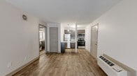 This single-floor unit offers a thoughtfully designed layout that balances functional living spaces with modern finishes throughout. The open living and dining area is anchored by warm wood-look laminate flooring and features a wall-mounted PTAC heating and cooling unit, with a sliding glass door that invites natural light into the space. The updated kitchen is a standout feature, showcasing gray shaker-style cabinetry, white quartz countertops, a subway tile backsplash in a soft metallic tone, and a full suite of stainless steel appliances including a refrigerator, electric range, microwave, and dishwasher. A pendant light above the kitchen peninsula adds a contemporary touch. Adjacent to the kitchen, a dedicated laundry area provides the convenience of an in-unit washer and dryer. The bedrooms are carpeted for comfort and each includes a ceiling fan with light fixture, along with sliding door access to the outdoors in at least one room. The bathroom is clean and functional, featuring a full tub and shower combination, a toilet, and wood-look tile flooring. Neutral wall tones and consistent trim details throughout create a cohesive and move-in-ready atmosphere.