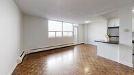 Located at 250 Lake St in St. Catharines, Ontario, this 2-bedroom, 1-bathroom unit offers a functional and comfortable layout across a single floor. Distinctive parquet wood flooring runs throughout the living areas and bedrooms, lending a warm, timeless character to the space.

The open living room is bright and spacious, benefiting from large windows that allow abundant natural light to fill the room. A balcony door provides direct outdoor access, enhancing the airy feel of the living area. Baseboard heating is present throughout, ensuring year-round comfort.

The kitchen is thoughtfully designed with white cabinetry, a classic subway tile backsplash, gleaming tile flooring, and stainless steel appliances including a refrigerator, stove, built-in microwave, and dishwasher. A peninsula with a dark countertop connects the kitchen to the living area, creating a practical and sociable space for dining and entertaining.

The primary bedroom is generously sized, offering a closet and a bright window with a baseboard heater beneath it. The second bedroom also features parquet flooring, a closet, and ample natural light. The bathroom is finished with white subway tile surrounding a full soaker tub and shower combination, maintaining a clean and classic aesthetic throughout.