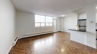 Located at 250 Lake St in St. Catharines, Ontario, this 2-bedroom, 1-bathroom unit offers a functional and comfortable layout across a single floor. Distinctive parquet wood flooring runs throughout the living areas and bedrooms, lending a warm, timeless character to the space.

The open living room is bright and spacious, benefiting from large windows that allow abundant natural light to fill the room. A balcony door provides direct outdoor access, enhancing the airy feel of the living area. Baseboard heating is present throughout, ensuring year-round comfort.

The kitchen is thoughtfully designed with white cabinetry, a classic subway tile backsplash, gleaming tile flooring, and stainless steel appliances including a refrigerator, stove, built-in microwave, and dishwasher. A peninsula with a dark countertop connects the kitchen to the living area, creating a practical and sociable space for dining and entertaining.

The primary bedroom is generously sized, offering a closet and a bright window with a baseboard heater beneath it. The second bedroom also features parquet flooring, a closet, and ample natural light. The bathroom is finished with white subway tile surrounding a full soaker tub and shower combination, maintaining a clean and classic aesthetic throughout.