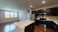 This single-story residence presents a well-designed open-concept layout that seamlessly connects the kitchen and living areas. The kitchen is a standout feature, equipped with dark espresso cabinetry, crisp white quartz countertops, and a full suite of stainless steel appliances, including a refrigerator, electric range, microwave, and dishwasher. A subway tile backsplash adds a clean, modern touch, while a central island provides additional counter space and storage. Rich hardwood flooring flows throughout the main living and kitchen areas, complementing the warm, neutral wall tones.

The living room is generously sized, outfitted with a ceiling fan, recessed lighting, and a sliding glass door that opens to a private balcony, allowing ample natural light. Bedrooms are carpeted for comfort, each featuring windows with blinds and ceiling fans. The bathrooms are finished consistently with dark vanity cabinetry, white countertops, hardwood-style flooring, and soaking tubs. At least one bathroom includes access to a walk-in closet with built-in shelving. A double-door closet near the kitchen provides additional storage throughout the unit.