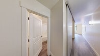 Located at 201 Yesler Way in Seattle's historic Pioneer Square neighborhood, this efficiently designed unit offers a well-considered layout across a single floor. The living area is highlighted by a large, multi-pane window framing direct views of the surrounding urban streetscape, with warm wood-look flooring and wall sconce lighting lending a clean, modern character throughout.

The kitchen is thoughtfully equipped with white cabinetry extending to the ceiling for ample storage, a dark countertop, a double sink, and a full suite of white appliances including a range, dishwasher, and refrigerator. The hallway connects the main living spaces and features a sliding barn-style door, adding a contemporary design touch.

The bedroom includes a dedicated closet with built-in shelving and rod, providing practical storage solutions. The bathroom is fitted with a tub-shower combination, a vanity with drawers and a mirror, and notably includes a stacked in-unit washer and dryer — a convenient feature for everyday living. Neutral walls and consistent wood-look flooring unify the space with a cohesive, understated aesthetic. The unit's central Pioneer Square location offers easy access to Seattle's waterfront, transit, and downtown core.