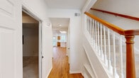 Located at 2925 Keller Springs Rd in Carrollton, TX, this two-story, three-bedroom, three-bathroom home offers a well-organized layout spread across two floors. The ground floor welcomes you through a defined entrance that flows into a bright, open-concept kitchen and living area. The kitchen is outfitted with warm oak cabinetry, white quartz countertops, a stainless steel sink, and ample natural light streaming through slatted window blinds. Warm hardwood flooring runs consistently throughout the main living areas, complemented by clean white walls that enhance the sense of brightness.

A staircase with a classic white balustrade and natural wood handrail connects the two floors. The upper level houses the three bedrooms, each featuring hardwood floors, ceiling fans, and windows that bring in natural light. The generously sized primary bedroom is accompanied by a walk-in closet with full wire shelving systems. The primary bathroom is well-appointed with dual oak vanities, white quartz countertops, a soaking tub, and tile flooring. Additional bathrooms feature single vanities with matching oak cabinetry. The attached garage offers a concrete floor and electrical panel access, providing practical utility space to complete this functional Carrollton home.