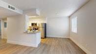 Located at 1201 Seminole Blvd in Largo, Florida, this single-floor residence offers a clean, contemporary design with thoughtfully updated finishes throughout. The open-concept layout connects the kitchen and living area seamlessly, creating a bright and airy atmosphere enhanced by abundant natural light from multiple windows dressed with vertical and horizontal blinds.

The kitchen is a standout feature, showcasing white shaker-style cabinetry, granite countertops, a stainless steel sink, and a full suite of stainless steel appliances including a refrigerator, range, microwave, and dishwasher. A breakfast bar provides a casual dining option while maintaining an open sightline to the living space.

Light wood-look flooring runs throughout the main living areas, lending a warm and cohesive feel, while the bedroom features plush carpeting for added comfort. The bedroom includes a generous closet with built-in shelving for ample storage.

Two bathrooms serve the residence, both finished with white cabinetry and granite-topped vanities. The full bathroom offers a tub and shower combination, while the second bathroom provides a well-appointed half-bath layout. The textured ceilings and crisp white walls round out the bright, move-in-ready interior.