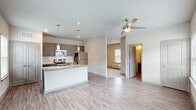 Located at 100 Still Creek Lane in Athens, GA, this single-floor unit offers a thoughtfully designed open-concept layout that maximizes its compact footprint. Light wood-look flooring flows throughout the entire space, creating a cohesive and contemporary feel.

The kitchen serves as a central hub of the home, featuring gray shaker-style cabinetry, granite countertops with a white subway tile backsplash, and a full suite of stainless steel appliances including a refrigerator, electric range, and over-the-range microwave. A peninsula with an undermount sink and pendant lighting above doubles as a breakfast bar, seamlessly connecting the kitchen to the open living area.

The living area is bright and airy, benefiting from multiple windows that invite natural light and a ceiling fan overhead. The bedroom continues this clean aesthetic with two windows offering neighborhood views, a ceiling fan, and access to a dedicated closet with wire shelving for organized storage.

The bathroom is well-appointed with a gray vanity topped with granite, a large mirror with vanity lighting, and a full tub-shower combination with white tile surround. Wood-look flooring carries through here as well, maintaining design consistency across the unit.