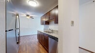 This three-bedroom, one-bathroom unit in Maplewood, Minnesota offers a practical and well-laid-out single-floor design. The kitchen is outfitted with rich dark wood cabinetry, granite-style countertops, a stainless steel sink, and a dishwasher, opening conveniently toward the living area which features wood-style flooring and a ceiling fan. The spacious living room benefits from a sliding glass door that brings in generous natural light and provides access to an outdoor area. Each of the three bedrooms is carpeted and features a ceiling fan, with baseboard heating units along the walls. The generously sized primary bedroom offers a comfortable retreat, while the additional bedrooms also provide ample space. A dedicated walk-in closet with dual hanging rods and shelving offers excellent storage capacity. The bathroom is clean and functional, featuring a full tub-shower combination, a toilet, wood-style flooring, and a vanity with matching dark wood cabinetry. A hallway connects the bedrooms and bathroom, contributing to a logical flow throughout the unit. Textured ceilings and warm wood-toned trim details are consistent throughout, giving the space a cohesive, tidy appearance.
