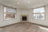 This single-floor urban residence offers a thoughtfully designed layout with a bright, open feel throughout. The living room is a standout space, anchored by a corner tile-surround fireplace and framed by multiple windows that fill the room with natural light and offer views of the surrounding cityscape. Recessed lighting complements the neutral tones and plush carpeting found throughout the living areas and bedrooms.

The kitchen features rich wood cabinetry, a breakfast bar peninsula, stainless steel appliances including a refrigerator and microwave, and stylish pendant lighting that creates an inviting atmosphere. It opens seamlessly to the main living and dining area, making it ideal for entertaining.

The primary bathroom is a well-appointed retreat, featuring a tiled soaking tub, a separate glass-enclosed shower, a wood vanity with dual sinks, and a striking diamond-pattern tile floor. A secondary bathroom provides a single vanity with warm wood cabinetry and clean, simple finishes. Additional bedrooms are carpeted and include ceiling fans and windows with urban views. A spacious walk-in closet with wire shelving offers ample storage. The overall ambiance is clean, neutral, and move-in ready, with an urban backdrop visible from nearly every room.