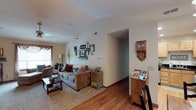 This single-floor home offers a thoughtfully designed layout with a welcoming flow between its key living spaces. The living room is a standout feature, boasting vaulted ceilings that lend an open, airy feel to the space. Warm hardwood-style flooring transitions to plush carpet, and a ceiling fan adds both style and function. Natural light filters in through a window dressed with decorative valances, creating an inviting atmosphere ideal for relaxing or entertaining.

The kitchen is equipped with light wood cabinetry featuring arched door profiles, rich dark granite countertops, an undermount sink, and a full suite of appliances including a gas range and stainless steel refrigerator — providing both practicality and visual appeal. Adjacent to the kitchen, the dining area accommodates a full dining set beneath a classic chandelier, with hardwood-style flooring and a direct sightline to the entry foyer.

The primary bedroom is generously proportioned with soft carpeting, a ceiling fan, and a closet with warm wood-toned doors. A secondary bedroom offers similar comfort with carpet flooring and easy hallway access. The bathroom features hardwood-style flooring, a shower with a curtain enclosure, a double-door closet for storage, and light teal-toned walls that create a calm, refreshing ambiance throughout.