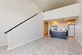 Located at 2502 Packard St in Ann Arbor, Michigan, this contemporary two-story residence offers a well-designed layout spread evenly across two floors. The main level immediately impresses with soaring ceilings and an open-concept living area anchored by a sleek, modern kitchen. The kitchen features two-tone cabinetry — warm light wood uppers paired with deep navy lower cabinets — complemented by white quartz countertops, stainless steel appliances including a range, microwave, and refrigerator, plus a bold navy center island with an integrated sink. Track lighting overhead and light-toned luxury vinyl flooring complete the polished look. A striking staircase with a clean white surround and black metal handrail connects the two floors, rising dramatically against a tall, open wall that enhances the sense of volume on the main level. The upper floor features a spacious bedroom with large windows that invite natural light and offer street-facing views. Both bathrooms are finished with natural wood vanities, white quartz countertops, and stylish geometric tile flooring. A dedicated laundry room houses a full-size side-by-side washer and dryer with open shelving. A closet provides additional storage. The overall aesthetic is clean, modern, and cohesive throughout.