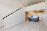 Located at 2502 Packard St in Ann Arbor, Michigan, this contemporary two-story residence offers a well-designed layout spread evenly across two floors. The main level immediately impresses with soaring ceilings and an open-concept living area anchored by a sleek, modern kitchen. The kitchen features two-tone cabinetry — warm light wood uppers paired with deep navy lower cabinets — complemented by white quartz countertops, stainless steel appliances including a range, microwave, and refrigerator, plus a bold navy center island with an integrated sink. Track lighting overhead and light-toned luxury vinyl flooring complete the polished look. A striking staircase with a clean white surround and black metal handrail connects the two floors, rising dramatically against a tall, open wall that enhances the sense of volume on the main level. The upper floor features a spacious bedroom with large windows that invite natural light and offer street-facing views. Both bathrooms are finished with natural wood vanities, white quartz countertops, and stylish geometric tile flooring. A dedicated laundry room houses a full-size side-by-side washer and dryer with open shelving. A closet provides additional storage. The overall aesthetic is clean, modern, and cohesive throughout.