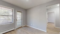 This single-floor unit in Hartford, CT offers a clean, modern aesthetic throughout its well-organized layout. Light wood-tone flooring flows consistently across all rooms, complementing the soft gray walls and crisp white trim that define the interior's cohesive palette.

The living area is generously proportioned, featuring multiple windows and a glass-paneled exterior door that floods the space with natural light and provides outdoor access. Baseboard heating runs along the perimeter, and an additional wall-unit air conditioner ensures year-round comfort. Architectural details such as decorative wainscoting panels add a touch of character near the entryway.

The kitchen is well-appointed with dark shaker-style cabinetry, marble-look countertops, a subway tile backsplash, and a full suite of stainless steel appliances including a refrigerator, dishwasher, and range. The layout makes efficient use of the available space while maintaining a polished, contemporary look.

The bedroom includes a set of double sliding closet doors offering ample storage. A separate open closet area is also visible near the entry zone, adding further organizational flexibility.

The bathroom features marble-look tile flooring, a rich dark wood vanity with a stone-top sink, a framed mirror, and clean white fixtures, creating a refined and functional space throughout.
