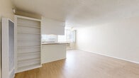 Located at 456 S Harvard Blvd in Los Angeles, CA, this one-bedroom unit offers a practical and well-laid-out single-floor design. Light wood laminate flooring runs throughout, complementing the neutral beige walls and white trim to create a clean, bright aesthetic. The open living area is generously sized, providing ample room for a variety of furniture arrangements, and features a textured ceiling and built-in HVAC ventilation. Natural light filters in through windows, enhancing the airy feel of the space. The kitchen is designed in a classic galley style, featuring white cabinetry with ample storage, granite-style countertops, a gas range, a refrigerator, and a sink with a window above it. A peninsula counter connects the kitchen to the living area, offering additional prep space and a casual dining option. Built-in shelving adjacent to the kitchen adds convenient storage. The bedroom is comfortably proportioned, featuring a large window that brings in natural light and views of the surrounding neighborhood. The textured ceiling and light flooring carry through from the main living areas, maintaining a cohesive design throughout the unit. This unit offers a straightforward, functional layout well-suited for comfortable city living in the Koreatown neighborhood of Los Angeles.