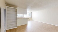 Located at 456 S Harvard Blvd in Los Angeles, CA, this one-bedroom unit offers a practical and well-laid-out single-floor design. Light wood laminate flooring runs throughout, complementing the neutral beige walls and white trim to create a clean, bright aesthetic. The open living area is generously sized, providing ample room for a variety of furniture arrangements, and features a textured ceiling and built-in HVAC ventilation. Natural light filters in through windows, enhancing the airy feel of the space. The kitchen is designed in a classic galley style, featuring white cabinetry with ample storage, granite-style countertops, a gas range, a refrigerator, and a sink with a window above it. A peninsula counter connects the kitchen to the living area, offering additional prep space and a casual dining option. Built-in shelving adjacent to the kitchen adds convenient storage. The bedroom is comfortably proportioned, featuring a large window that brings in natural light and views of the surrounding neighborhood. The textured ceiling and light flooring carry through from the main living areas, maintaining a cohesive design throughout the unit. This unit offers a straightforward, functional layout well-suited for comfortable city living in the Koreatown neighborhood of Los Angeles.