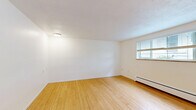 Located at 1550 Detroit St in Denver's desirable Congress Park neighborhood, this efficient single-floor unit offers a thoughtfully organized layout comprising a living room, kitchen, and bathroom. The living room is a bright, open space featuring warm hardwood flooring, crisp white walls, and multiple windows fitted with blinds that invite natural light while maintaining privacy. A wall-mounted air conditioning unit and baseboard heating ensure year-round comfort, and a distinctive blue entry door adds a pop of personality to the clean, neutral interior. The kitchen is well-equipped with white shaker-style cabinetry, a classic subway tile backsplash, and stainless steel appliances including a range and refrigerator. Elegant marble-look tile flooring grounds the space and adds a refined touch. A range hood and under-cabinet lighting contribute to both function and ambiance. The bathroom features a full bathtub with clean white square tile surround, maintaining the consistent, bright aesthetic found throughout the unit. Overall, this space presents a clean, modern, and functional design with cohesive finishes, making efficient use of its footprint in one of Denver's most sought-after urban neighborhoods.